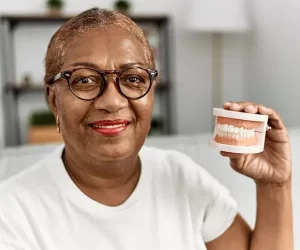 DentureDenture Smiling person holding dental model with dentures.
