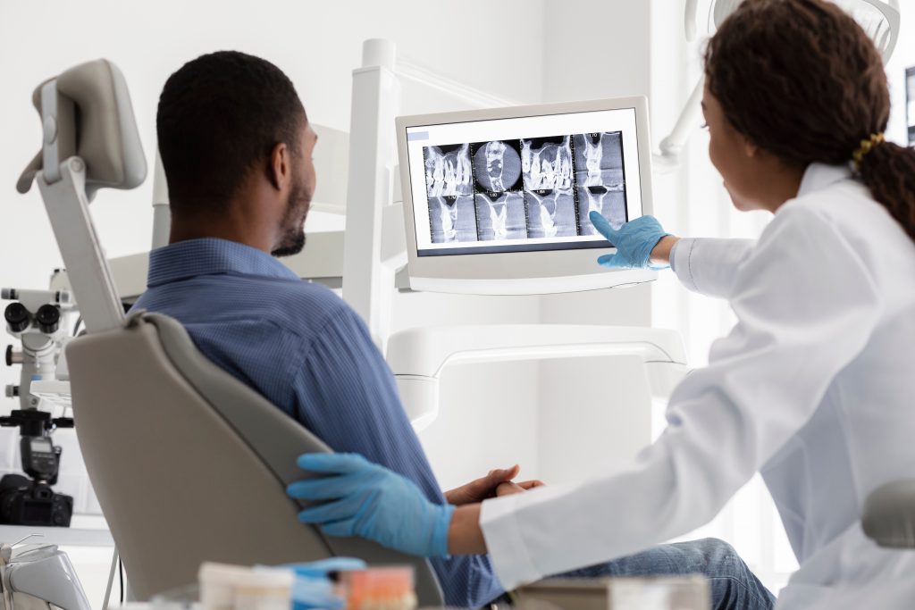 Dentist showing patient dental cleaning X-ray images.