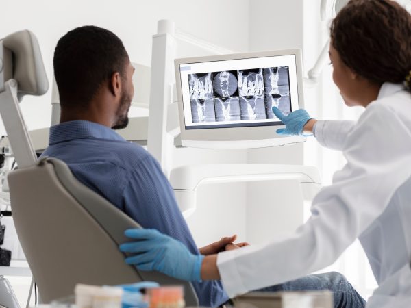 Dentist showing patient dental cleaning X-ray images.