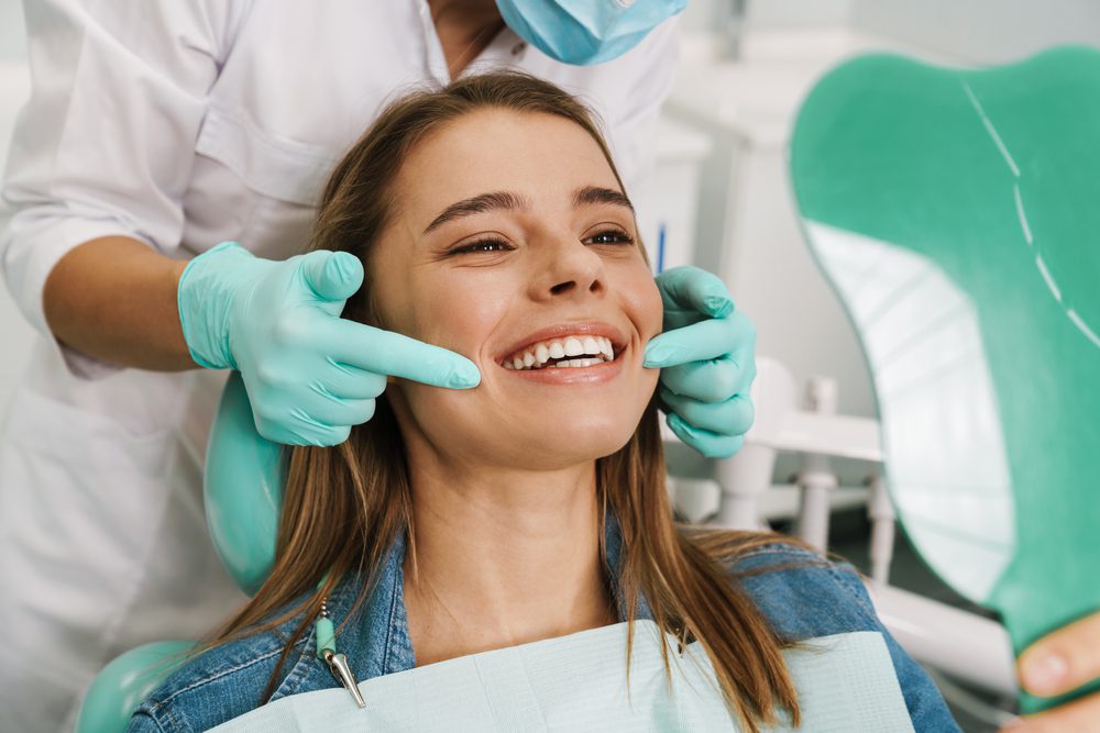 European,Young,Woman,Smiling,While,Looking,At,Mirror,In,Dental Woman smiling during dental checkup