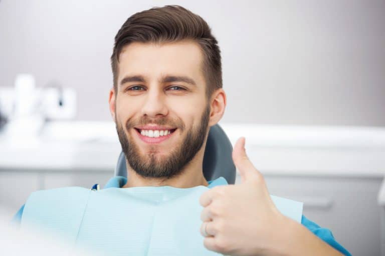 service-checkup-768x512 Smiling man at dentist's office gives thumbs up.